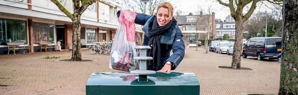 vrouw gooit kleding in textiel container