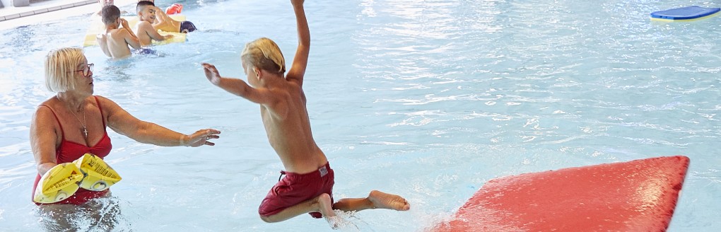 Jongen springt van mat in het water