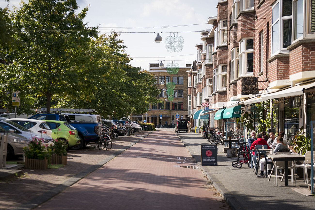 De Vlierboomstraat, richting de Appelstraat. Met winkelgevels en een klein terras rechts.