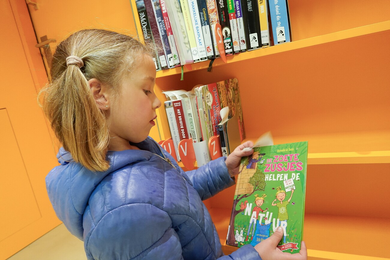 Een meisje zoekt een boek uit in de bibliotheek