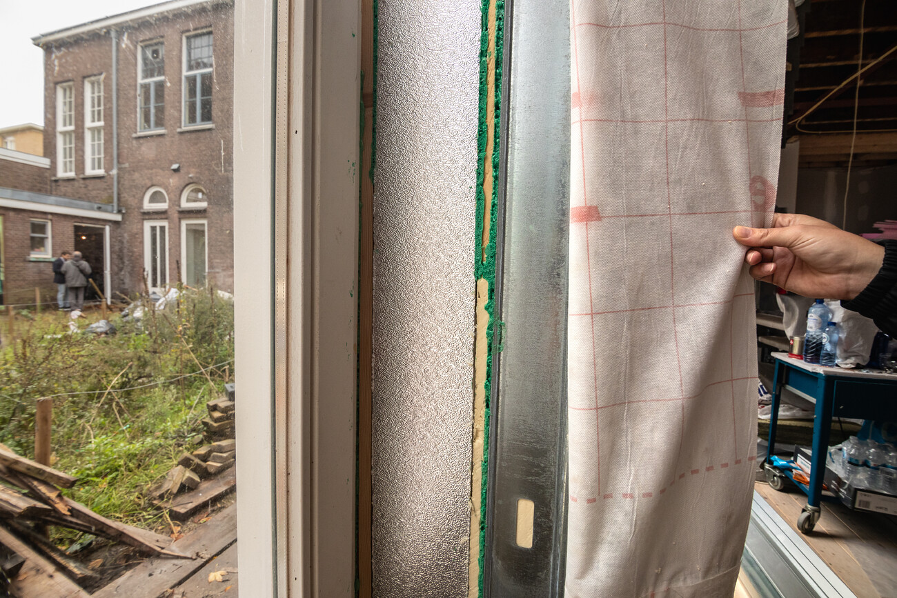 Verschillende lagen van isolatie in een woning bij een raam.