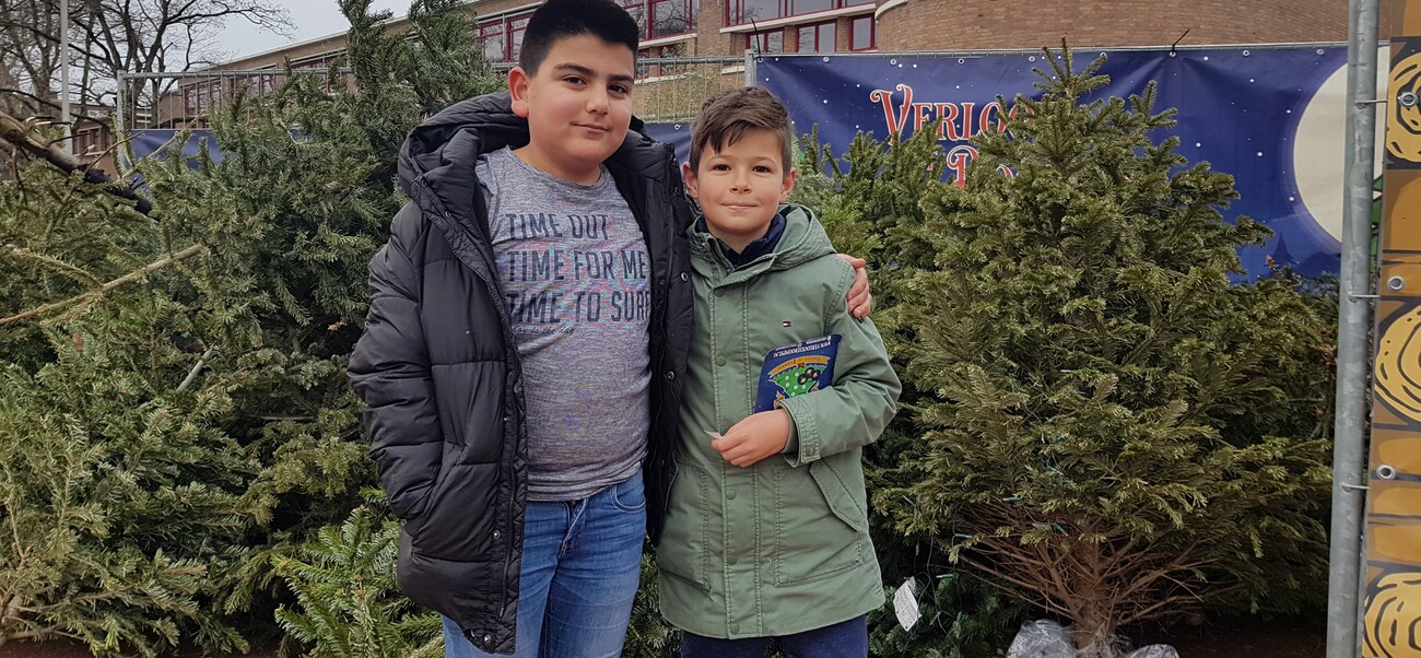 2 jongens bij de ingeleverde kerstbomen voor de actie 'Verloot je Boompje'