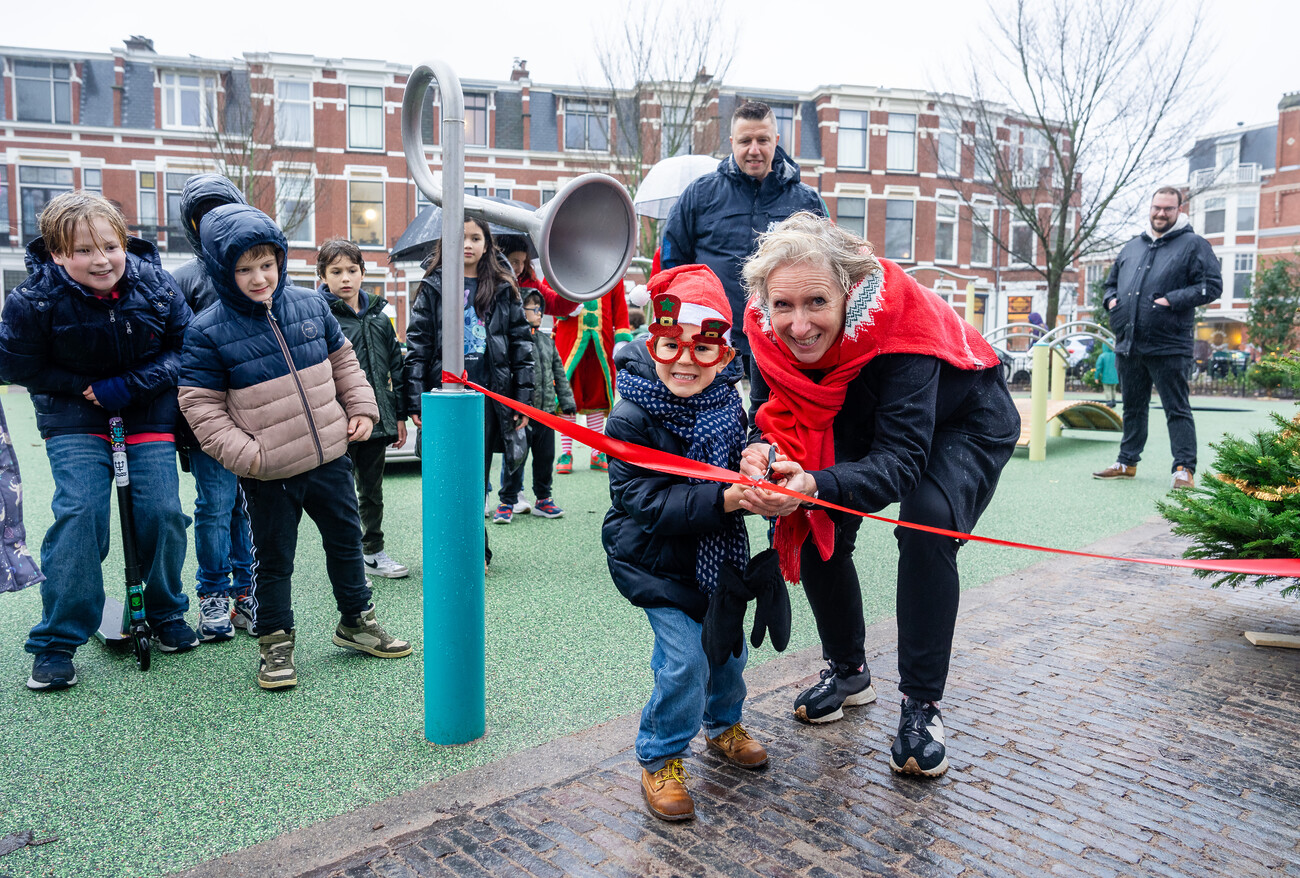 Stadsdeeldirecteur Mandy van Veen knipt samen met een kind een lintje door om de speeltuin op het Frederik Hendrikplein feestelijk te openen.