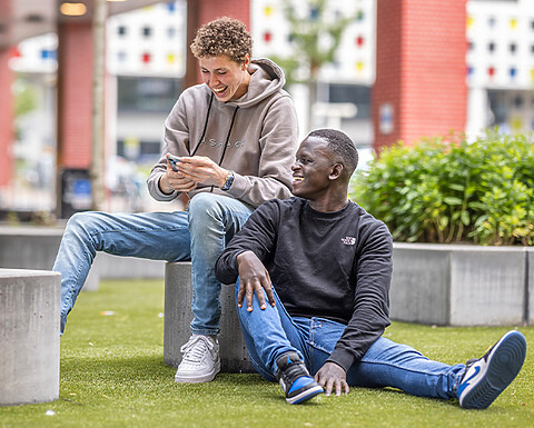 2 jongens tijdens een pauze lachen met elkaar