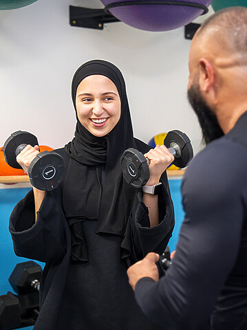 Meisje doet aan fitness en heeft 2 gewichten in haar handen