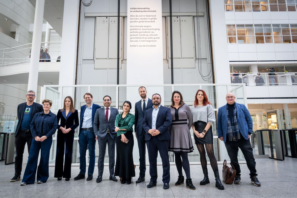 Haagse wethouders en raadsleden in het Haagse stadhuis voor de liftschacht met de tekst: Gelijke behandeling en verbod op discriminatie. Allen die zich in Nederland bevinden, worden in gelijke gevallen gelijk behandeld. Discriminatie wegens godsdienst, levensovertuiging, politieke gezindheid, ras, geslacht, handicap, seksuele gerichtheid of op welke grond dan ook, is niet toegestaan. Artikel 1 van de Grondwet