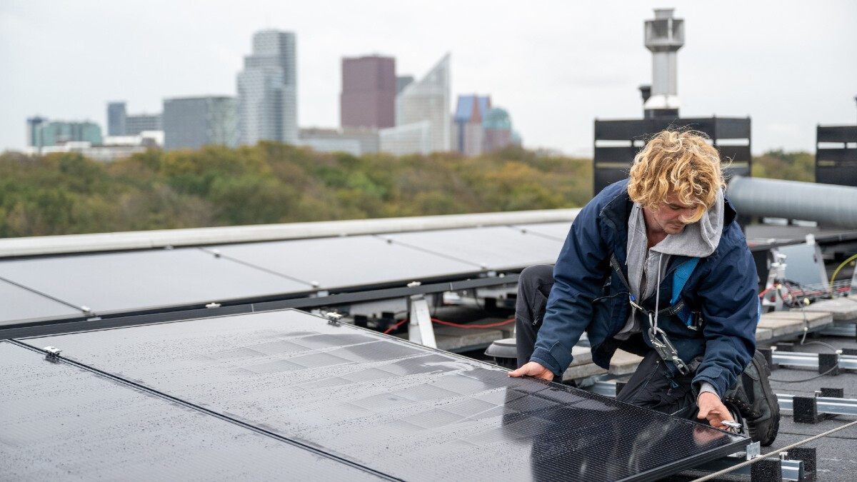 Foto van een man die zonnepanelen plaatst op een dak in Den Haag.