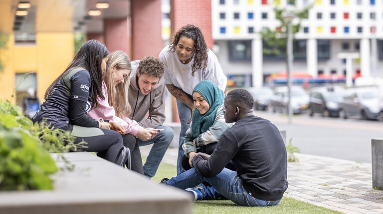 Groep van 6 jongeren buiten op een plein