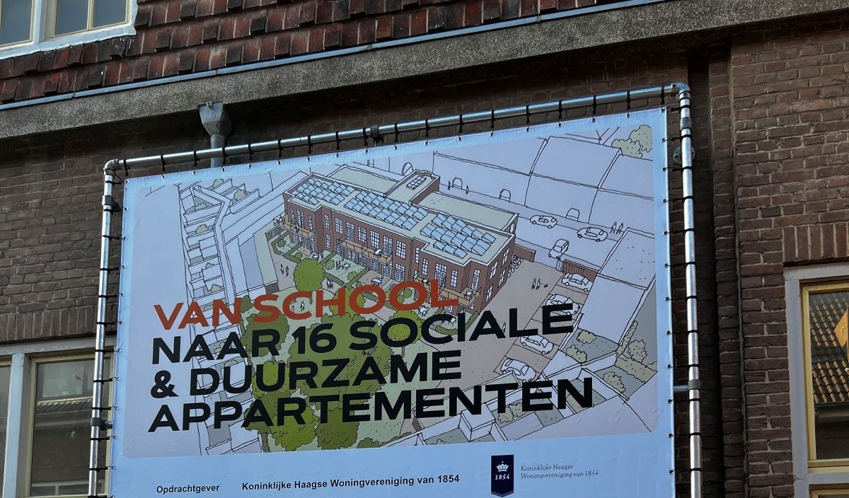 Bord op de gevel van school in Duindorp met de tekst 'Van school naar 16 sociale duurzame appartementen'