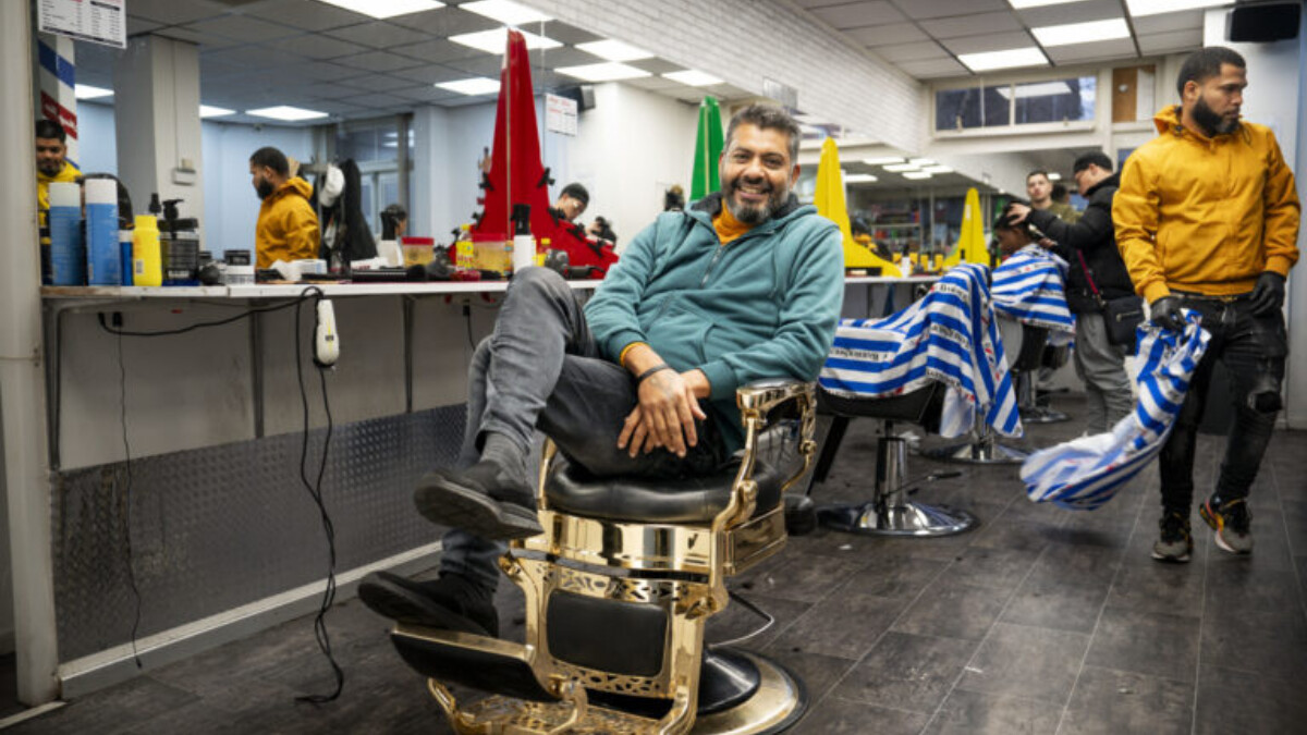 Deepak Mahabier op 1 van de kappersstoelen in zijn barbershop in Laak.