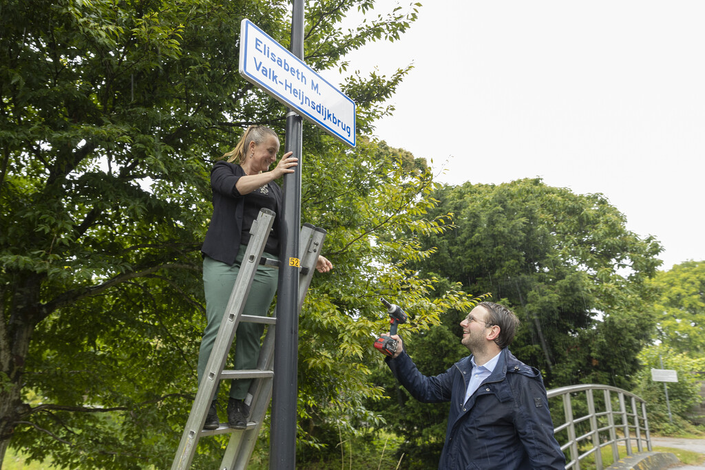 Wethouder Robert Barker overhandigt gereedschap aan Freya van Wageningen (eigenaresse van veganistisch restaurant Hagedis) voor de bevestiging van het naambord.